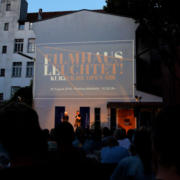 Der Filmhaus Innenhof mit erleuchteter Fassade und Publikum