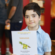 Ein junge hält stolz eine Teilnahmeurkunde zum Bielefelder Kinder- und Jugendfilmwettbewerb 2023 hoch
